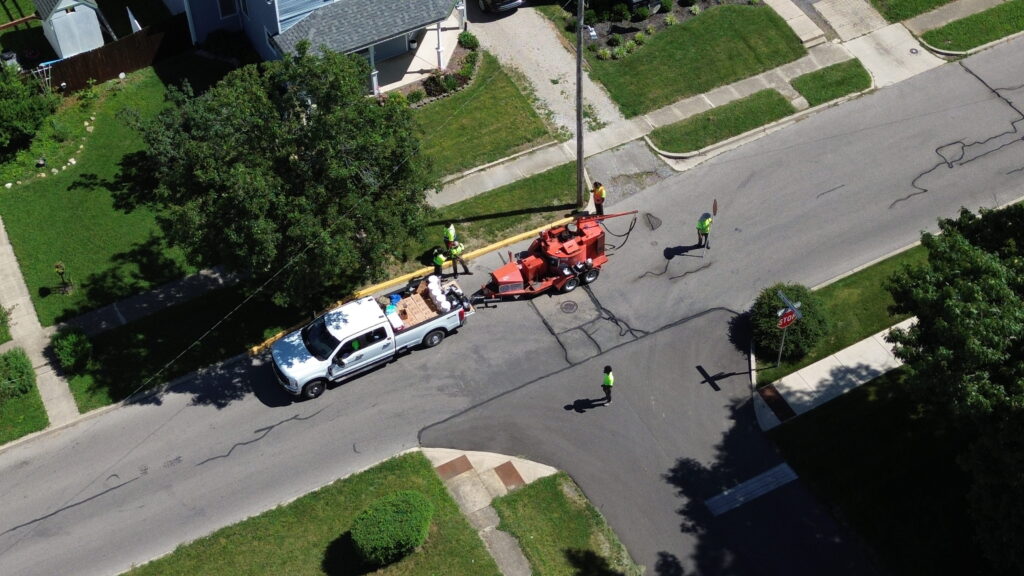 Drone view of a roadway maintenance crew crack sealing a street intersection