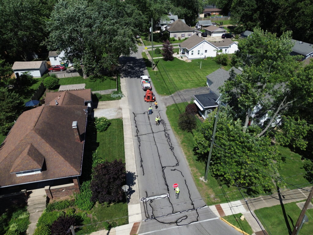 Fresh hot-applied crack sealant lines on an asphalt street during roadway maintenance