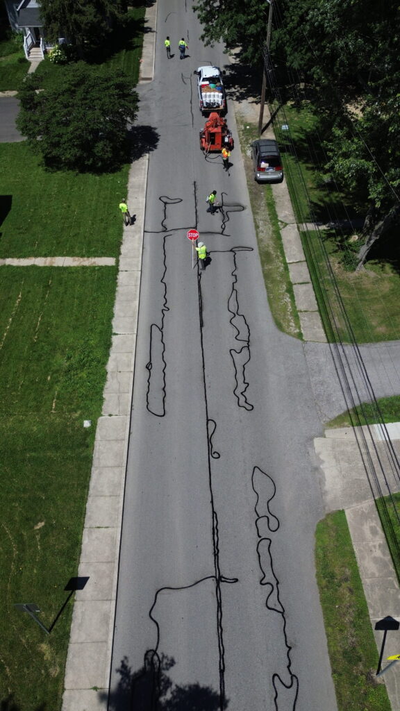 Overhead view of sealed pavement cracks running down a residential street after preventative roadway maintenance.